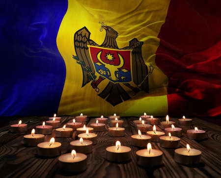 Mourning candles burning on Moldova national flag of background. Memorial weekend, patriot veterans day, National Day of Service Remembrance. Burning candles on wooden surface. 3d illustration.の写真素材