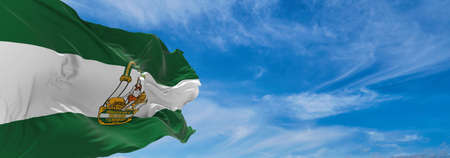 flag of Andalucia , Spain at cloudy sky background on sunset, panoramic view. Spanish travel and...