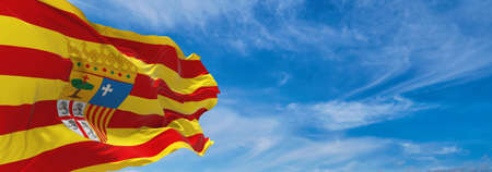 flag of Aragon , Spain at cloudy sky background on sunset, panoramic view. Spanish travel and patriot concept. copy space for wide banner. 3d illustrationの写真素材