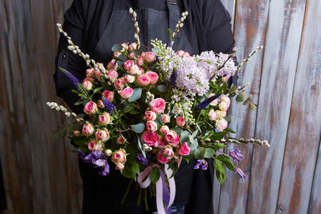 a woman holding a beautiful colourful blossoming flower bouquet. Fresh, lush bouquet of colorful flowersの写真素材