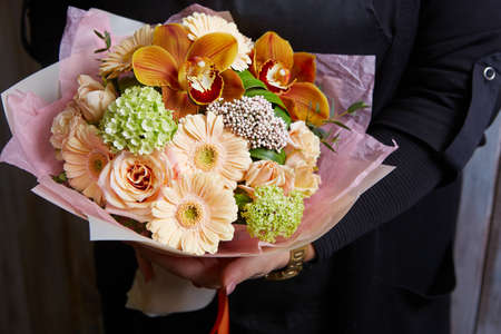 a woman holding a beautiful colourful blossoming flower bouquet. Fresh, lush bouquet of colorful flowersの写真素材