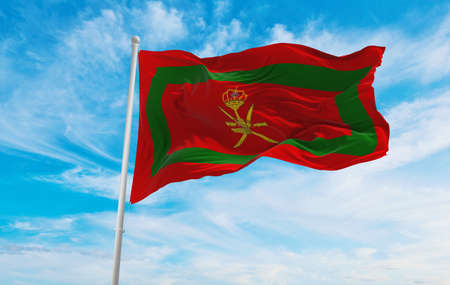 Royal Standard of Oman flag at cloudy sky background on sunset, panoramic view. Oman travel and patriot concept. copy space for wide banner. 3d illustrationの写真素材