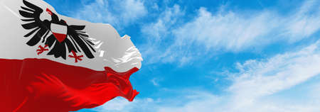 flag of Hansestadt Lubeck at cloudy sky background on sunset, panoramic view. Federal Republic of Germany. copy space for wide banner. 3d illustrationの写真素材