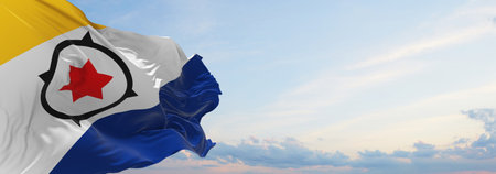 flag of Bonaire , Netherlands at cloudy sky background on sunset, panoramic view. Dutch travel and patriot concept. copy space for wide banner. 3d illustrationの写真素材