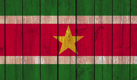 Top view of Old Painted Flag of Suriname on Dark Wooden Fence, wall. patriot and travel concept. no flagpole. Plane design, layout. Flag backgroundの写真素材