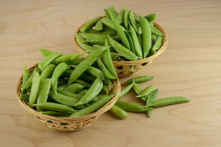 Green snap beans in wood baskets in preparation for removing strings