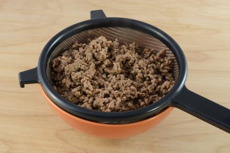 Draining fat and grease from cooked hamburger meat in strainer in bowl for spaghetti sauce