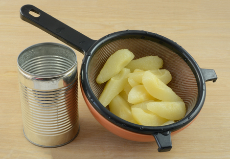 Canned Bartlett pear slices in strainer in bowl with canの写真素材