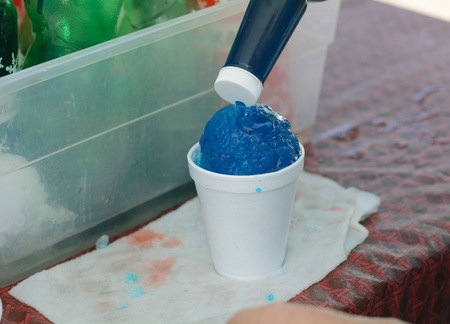 Pouring blueberry syrup onto snow cone at farmer's marketの写真素材