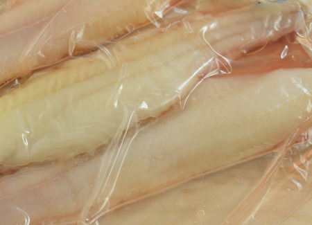 Frozen raw catfish fillets thawing in plastic packagingの写真素材