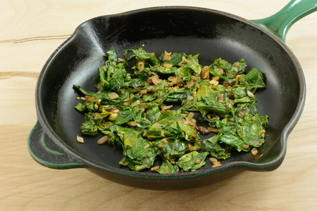 Sauteed collard greens with chopped shallot in cast iron frying pan skilletの写真素材