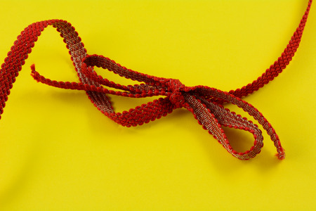 Red and gold ribbon and tied bow on yellow backgroundの写真素材