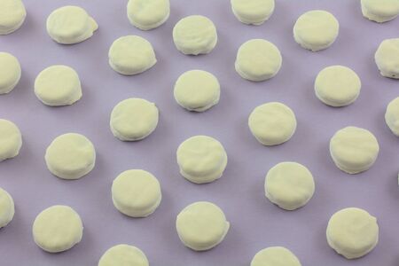 Mini cookies dipped in white fudge in a row on lavender backgroundの写真素材