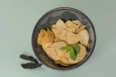 Lamb and mint potato crisps in bowl with fresh mint leaves on light green backgroundの写真素材