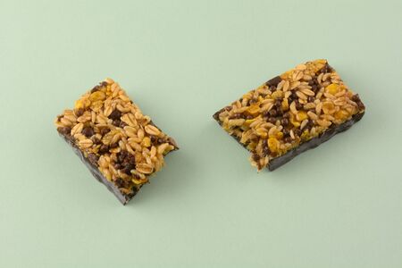 Dark chocolate and rice candy bar snack halves on light green backgroundの写真素材