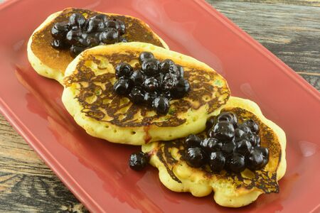Cornmeal pancakes with jalapeno with blueberry sauce topping on red serving platter