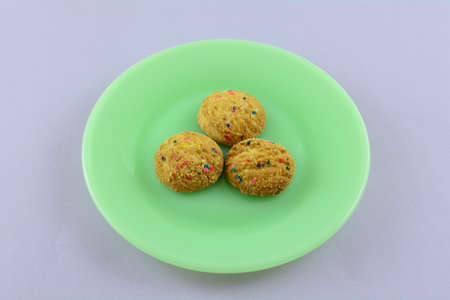 Three small bite size candy bead cookies on green plate on lavender background