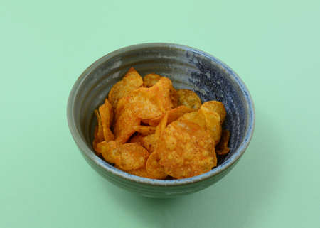 Kettle Style BBQ Potato Chips in ceramic snack bowl on green background
