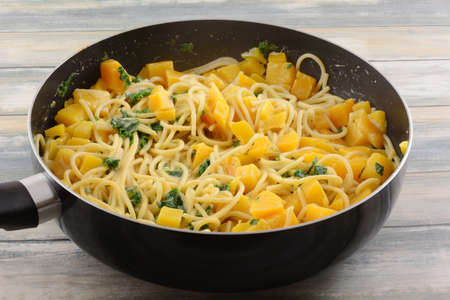 Scallops with kale and butternut squash vegetable pasta dish in frying panの写真素材