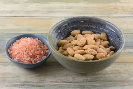 Himalayan pink salt and whole almonds salted with pink Himalayan salt in bowls on table