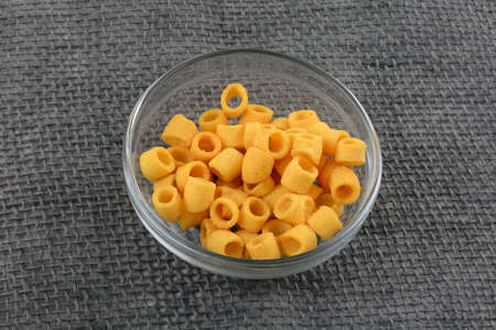 Bowl with corn rings on grey background, top view. Space for text