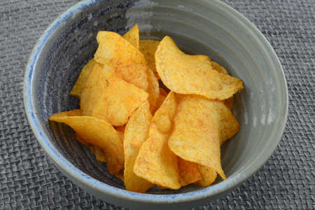Crispy corn chips in a bowl on a gray tablecloth