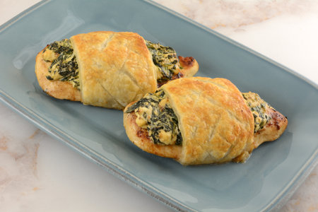 Puff pastry filled with spinach and cheese on a blue plateの写真素材