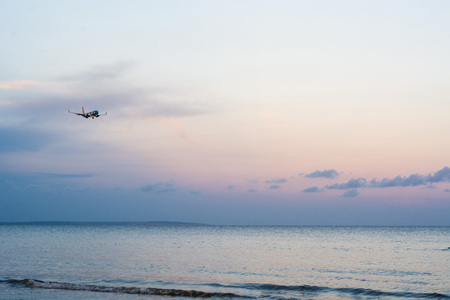 Airplane flying above sea at sunsetの写真素材