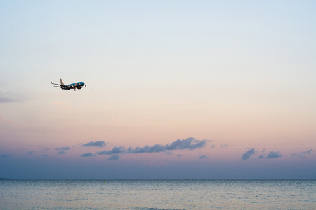 Airplane flying above sea at sunsetの写真素材