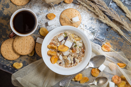 Flat lay of a rustic style with cereal, dried fruits, coffee and cookies on a wooden tableの写真素材