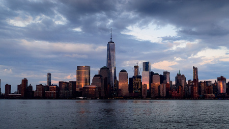 Panoramic view of Manhattan skyline with its reflection in Hudson river at dusk from New Jersey...