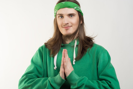 Portrait of young handsome smiling happy man in green hoodie looking at the camera and showing namaste agains white background. Lifestyle and peopleの写真素材