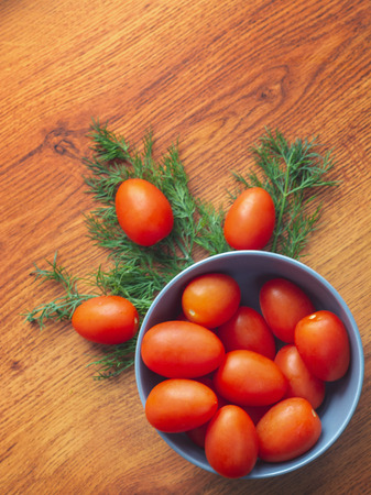 Fresh ripe cherry tomatoes in the blue bowl with fresh dill, overhead shot.の写真素材