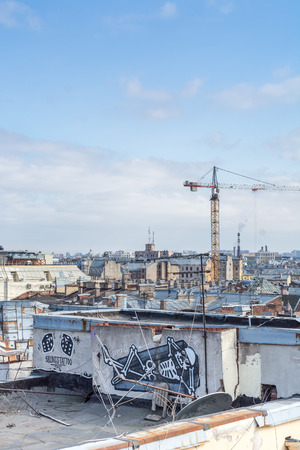 Saint Petersburg, Russia - April 2018: View of the city from the roof of old houses in historical downtown at sunny day, construction cranes  and graffiti.のeditorial素材