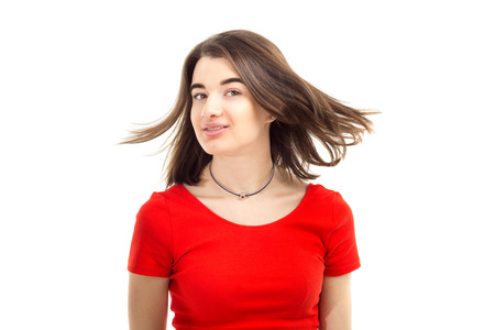 Closeup portrait of a young happy smiling girl in red t-shirt, wind blows her hair against white background.の写真素材
