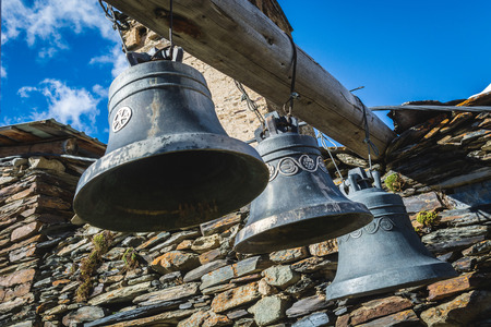 Bells in Lamaria church in Zhibiani - Ushguli community of villages, Upper Svaneti, Georgia, view from below with blue sky backgroundの写真素材