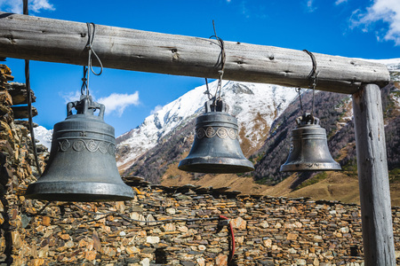 Bells in Lamaria church in Zhibiani - Ushguli community of villages, Upper Svaneti, Georgia. Snow covered peak of Shkhara mountain on backgroundの写真素材