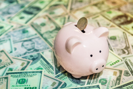 Piggy bank with Quater dollar coin on background of dollar bills, savings and investments concept, tonedの写真素材