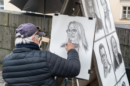Prague, Czech Republic - December 2018: A street artist painting a portrait from the photograph on the Charles bridgeのeditorial素材
