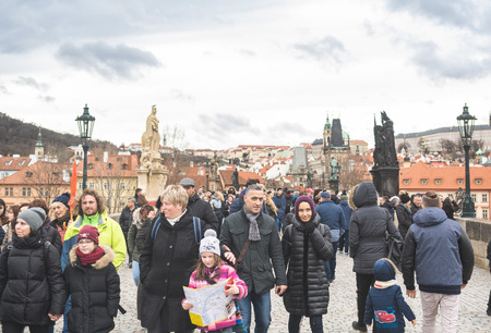 Prague, Bohemia  Czech Republic - December 2018: Tourists walking on the famous Charles Bridge (Karluv most) on cloudy winter day, statues and dramatic skyのeditorial素材
