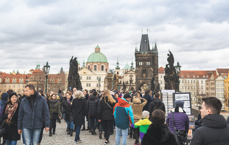 Prague, Bohemia  Czech Republic - December 2018: Tourists walking on the famous Charles Bridge (Karluv most) on cloudy winter day, statues and dramatic skyのeditorial素材