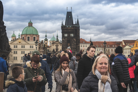 Prague, Bohemia  Czech Republic - December 2018: Tourists walking on the famous Charles Bridge (Karluv most) on cloudy winter day, statues and dramatic sky, selective focusのeditorial素材
