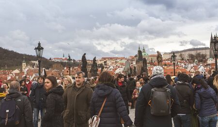 Prague, Bohemia  Czech Republic - December 2018: Tourists walking on the famous Charles Bridge (Karluv most) on cloudy winter day, statues and dramatic sky, selective focusのeditorial素材