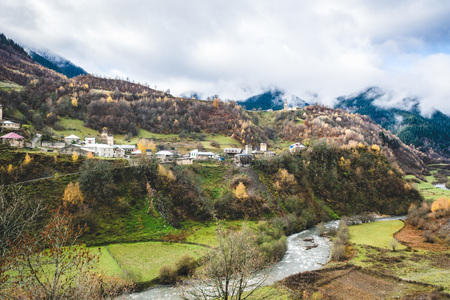 Panoramic view of small town placed on green hills of mountain valley in clouds, Svanetiの写真素材