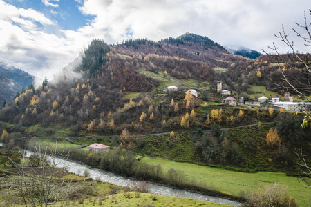 Panoramic view of small town placed on green hills of mountain valley in clouds, Svanetiの写真素材