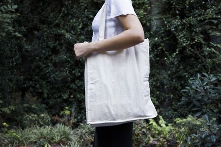 Blank white shopping canvas fabric cloth bag on female holding mockup and template isolated natural...