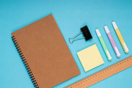 Notebook, colored pencils, ruler, note paper and clamp. back to school isolated blue background