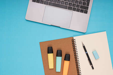 Laptop, notepad, pencil, eraser, colored pencils. back to school isolated blue backgroundの写真素材