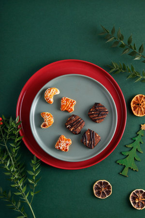 Christmas decorations and flowers on an isolated green background, cookies on a plateの写真素材