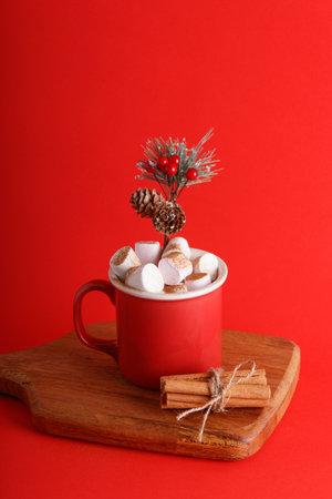 Red mug full of hot chocolate and marshmallows on an isolated red background, new year and christmas themeの写真素材